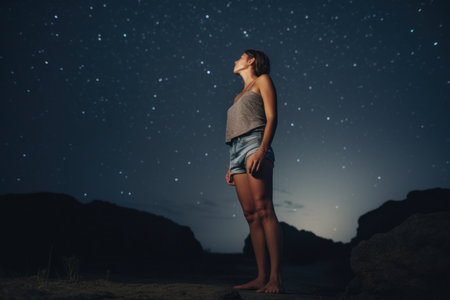 Young woman standing on the beach and looking at the starry skyの素材