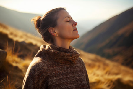 Portrait of a young woman in a sweater and scarf on the background of mountainsの素材
