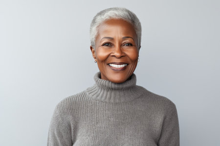 Close up portrait of smiling african american woman in gray sweater against white backgroundの素材