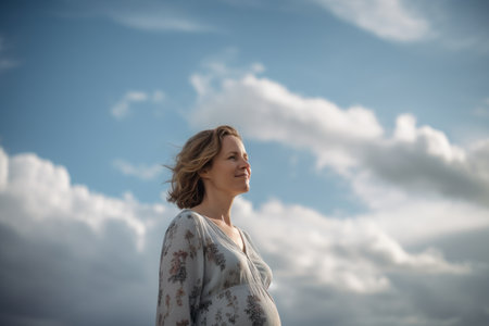 Pregnant woman on the background of blue sky with clouds.の素材