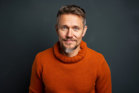 Portrait of a mature man in orange sweater looking at camera.の素材