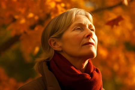 Portrait of a beautiful senior woman in the autumn forest at sunsetの素材