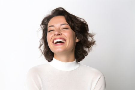 Portrait of a beautiful young woman laughing on a white background.の素材