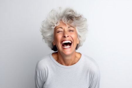 Portrait of a happy senior woman laughing on a white background.の素材
