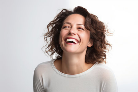 Portrait of a happy young woman laughing on a white background.の素材