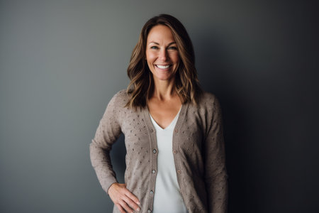 Portrait of a happy pregnant woman looking at camera and smiling while standing against gray backgroundの素材