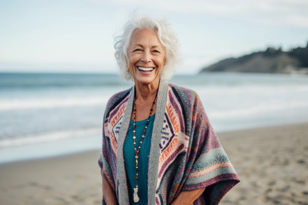 Portrait of happy senior woman standing on beach and looking at cameraの素材