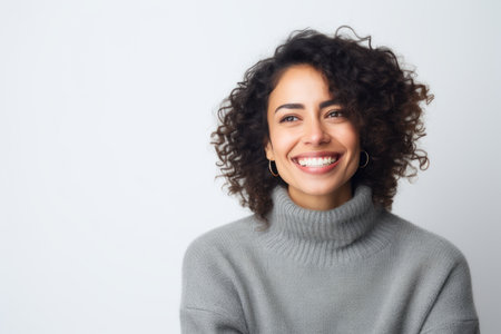 Portrait of a smiling young woman with curly hair against white backgroundの素材