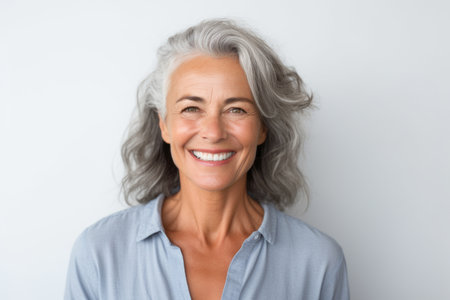 Portrait of a happy senior woman smiling at camera over white backgroundの素材