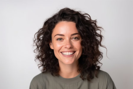 Portrait of a smiling young woman with curly hair on a white backgroundの素材