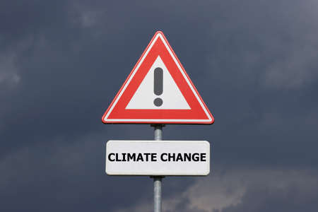 A sign with an exclamation mark warning for a dangerous situation ahead and a smaller sign below with the English text Climate Change on itの写真素材