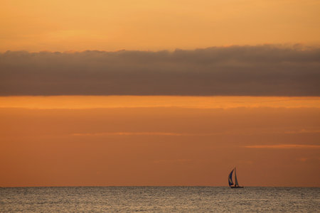 A small sailing boat on the open sea at sunsetの写真素材