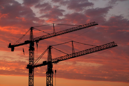 Two large at a construction site against a colorful sky at sunsetの写真素材