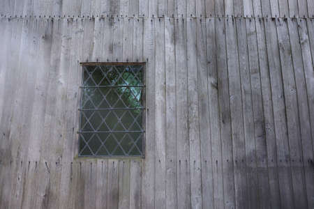 A wooden wall of a building with a window made of stained glass in itの写真素材