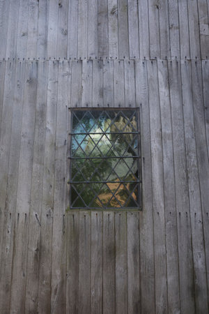 A wooden wall of a building with a window made of stained glass in it