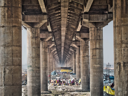 People and tents under the main bridge crossing over the massive Kumbh Mela festival in Allahabad, India のeditorial素材