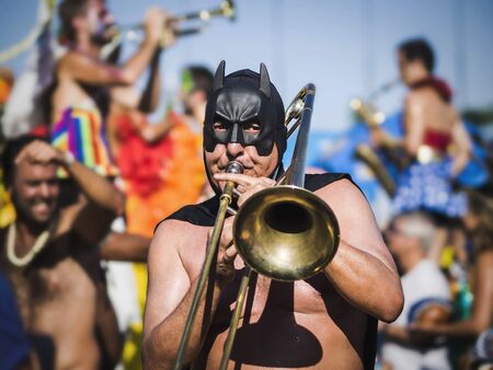 Rio de Janeiro, Brazil - February 9, 2016: Masked musician playing the trombone with Bloco da Orquestra Voadora during Carnaval 2016 parade in Rio de Janeiro, Brazil.のeditorial素材