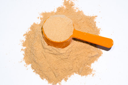 Protein powder with it measuring cup full on top, on white backgroundの写真素材