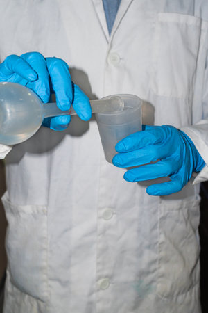 Men pouring acid in a beaker, with blue glovesの写真素材