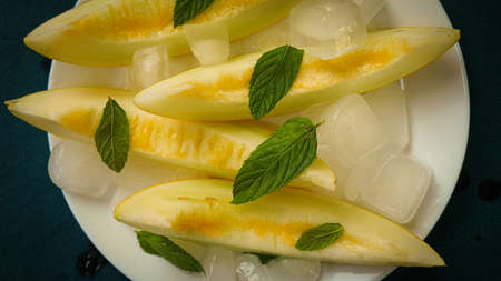 ripe melon with crushed ice and mint leaves, cut into pieces and slicesの写真素材