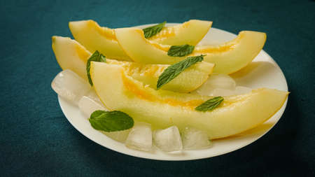 ripe melon with crushed ice and mint leaves, cut into pieces and slicesの写真素材