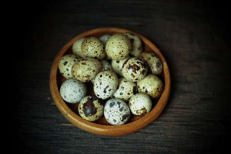 Fresh quail eggs close up on a wooden table small hard boiled eggs rustic top viewの写真素材
