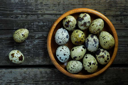 Fresh quail eggs close up on a wooden table small hard boiled eggs rustic top viewの写真素材