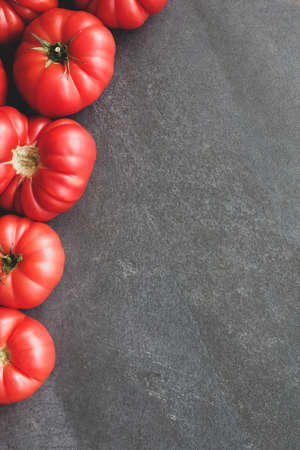 Organic Ripe and Juicy Tomatoes on Dark Stone Table Flat Lay Copy Spaceの写真素材