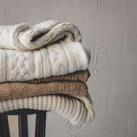 Warm Winter Female Woolen Knitted Sweaters Stack on Wooden Stool at Gray Background Women Fashion Composition Copy Spaceの写真素材