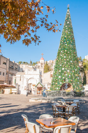 NAZARETH, ISRAEL - DEC 23, 2013  Local and visitors in front of a Christmas tree with the Nativity Scene, Near the Greek Orthodox Church of the Annunciation, in Nazareth, Israelのeditorial素材