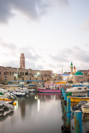 ACRE, ISRAEL - JULY 17, 2014  Local fishing boats, yachts with and nearby monuments, at sunset in...