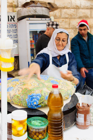NAZARETH, ISRAEL - December 19, 2014: A woman preparing pita bread, in a Christmas market food stall, in Nazareth, Israelのeditorial素材
