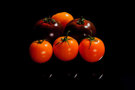 Light and dark tomatoes on a black surfaceの写真素材