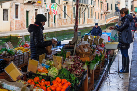 VENICE, ITALY - FEB 04, 2015: Scene of floating vegetable store, near San Barnaba square, with local and tourists, in Venice, Veneto, Italyのeditorial素材