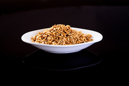 Roasted Salted Sunflower Seeds in a white plate on a black backgroundの写真素材