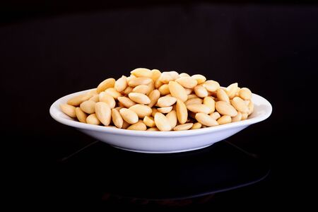 Blanched Almonds in a white plate on a black backgroundの写真素材