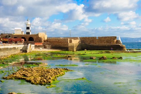 ACRE ISRAEL  MAY 04 2015: Scene of a Templar Fortress remains lighthouse restaurants local fishermen and Haifa bay in the old city of Acre Israelのeditorial素材