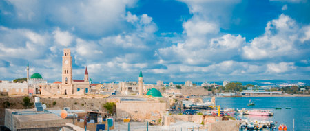 ACRE ISRAEL  MAY 04 2015: Sunset scene of the fishing harbor rooftop view with the clock tower minarets of Sinan Basha Mosque and AlJazzar mosque other monuments local business and visitors. Acre Israelのeditorial素材