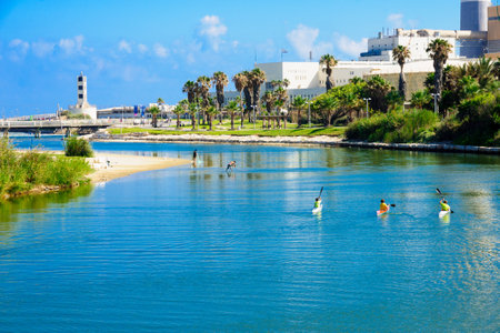 TEL AVIV ISRAEL  JUNE 12 2015: Scene of rowers in the Yarkon stream fishermen the Reading Power Station the lighthouse and the Wauchope Bridge in TelAviv Israelのeditorial素材