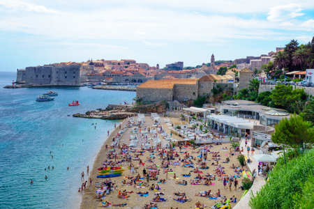 DUBROVNIK, CROATIA - JUNE 26, 2015: Beach scene, with the old city and its port, locals and tourists, in Dubrovnik, Croatiaのeditorial素材