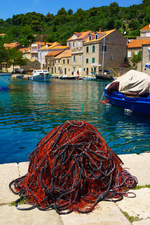 SUDURAD, CROATIA - JUNE 27, 2015: Scene of the fishing port, with a fishing net, boats, locals and tourists, in the village Sudurad, Sipan Island, one of the Elaphiti Islands, Croatiaのeditorial素材