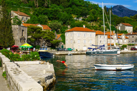 PERAST, MONTENEGRO - JUNE 28, 2015: Scene of the promenade, with cafes, old buildings, boats, locals and tourists, in Perast, Montenegroのeditorial素材