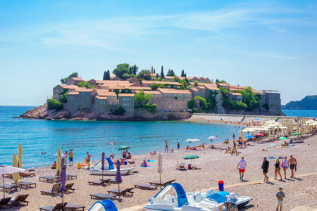 SVETI STEFAN, MONTENEGRO - JUNE 29, 2015: Beach scene, with the old village, locals and tourists, in Sveti Stefan, Montenegroのeditorial素材