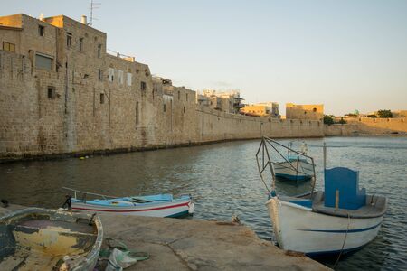 Fishing nets and boats, and the old sea wall in the old city of Acre, Israelの写真素材