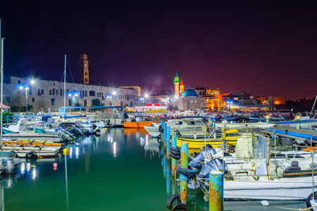 ACRE, ISRAEL - OCTOBER 18, 2015: Local fishing boats, yachts with and nearby monuments, at night in the fishing harbor in the old city of Acre, Israel. Acre was a major harbor city for many centuriesのeditorial素材