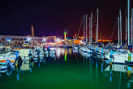 ACRE, ISRAEL - OCTOBER 18, 2015: Local fishing boats, yachts with and nearby monuments, at night in the fishing harbor in the old city of Acre, Israel. Acre was a major harbor city for many centuriesのeditorial素材