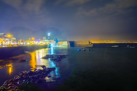 ACRE, ISRAEL - OCTOBER 18, 2015: Night scene of a Templar Fortress remains, lighthouse, restaurants, visitors and Haifa bay, in the old city of Acre, Israelのeditorial素材