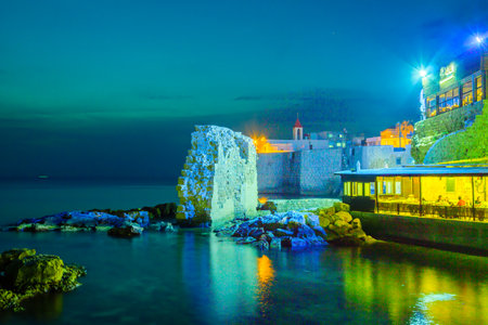 ACRE, ISRAEL - OCTOBER 18, 2015: The sea wall and St. John the Baptist Franciscan church at night, with local diners, in the old city of Acre, Israelのeditorial素材