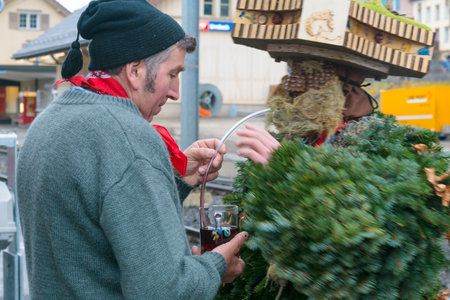 URNASCH, SWITZERLAND - DECEMBER 31, 2015: Local residents serve a drink to the New Year Mummers, in Urnasch, Appenzell, Switzerland. The Silvesterchlausen is a tradition of greeting for the New Yearのeditorial素材