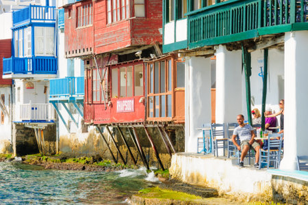 MYKONOS, GREECE - OCTOBER 02, 2011: Village and beach scene, with little Venice houses, local businesses, locals and visitors, in Mykonos, Mykonos Island, Greeceのeditorial素材